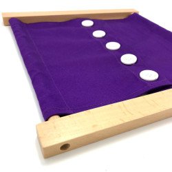 Cadre d'habillage Montessori tissu violet et grands boutons blancs vu de trois quarts.