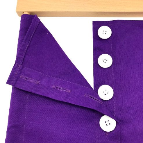 Cadre d'habillage Montessori tissu violet et grands boutons blancs vu de détail avec les boutons en partie ouverts.