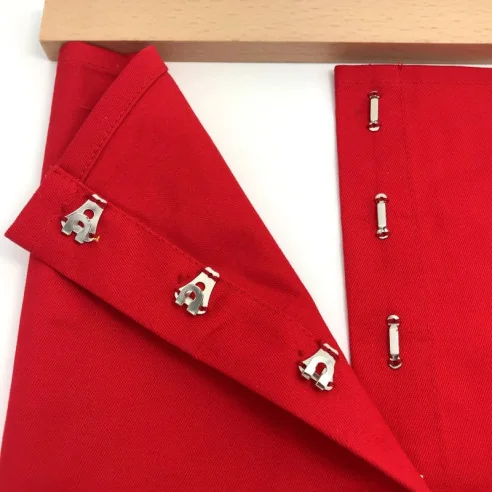 Cadre d'habillage agrafes Montessori de couleur rouge, vue de détail avec les agrafes ouvertes.
